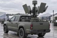 Rotating electronic warfare jamming module with directional antennas mounted on a pickup truck bed at an outdoor defence exhibition