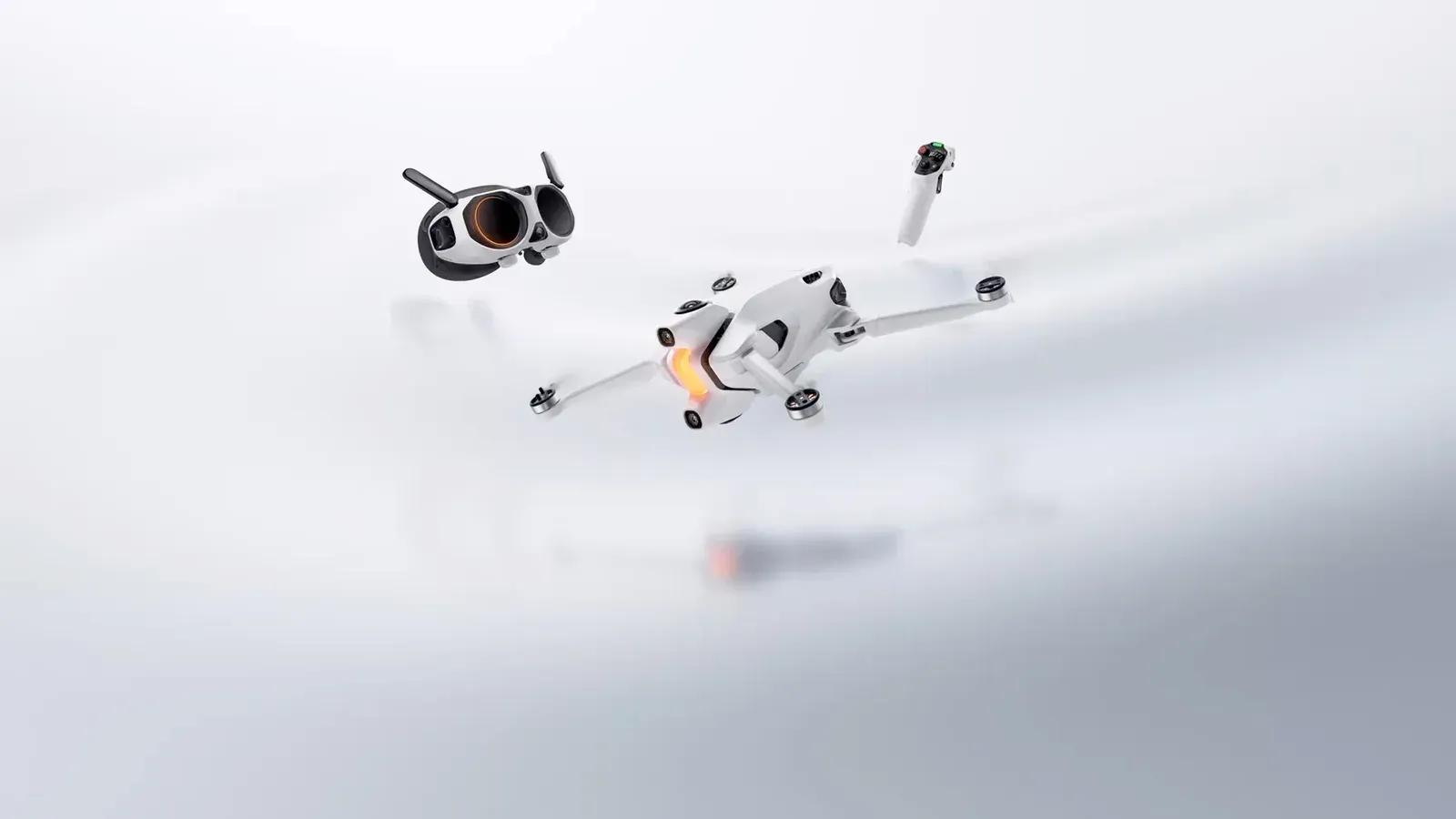 White Antigravity A1 quadcopter in flight beside its white goggles and a single-hand grip controller against a pale grey studio background