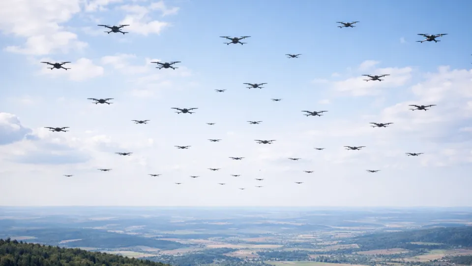 Multiple small drones flying in formation representing the emerging drone swarm threat to military bases