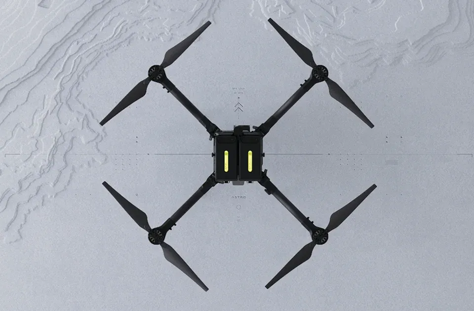 Freefly Astro quadcopter seen from directly above, with two batteries in its centre, on a pale topographic background