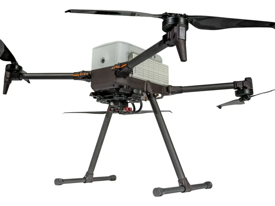 Inspired Flight IF800 Tomcat quadcopter with carbon-fibre arms, folding propellers and tall landing legs, seen from slightly below, on a white background