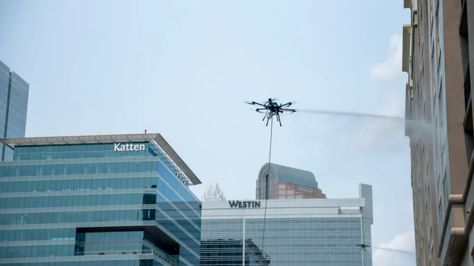 Lucid Bots Sherpa hexacopter drone cleaning a glass building facade at height