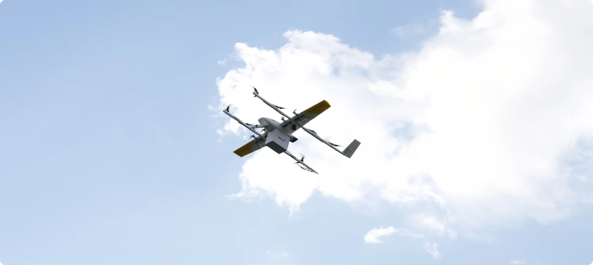 Wing drone in flight over a suburban neighborhood during a Walmart delivery