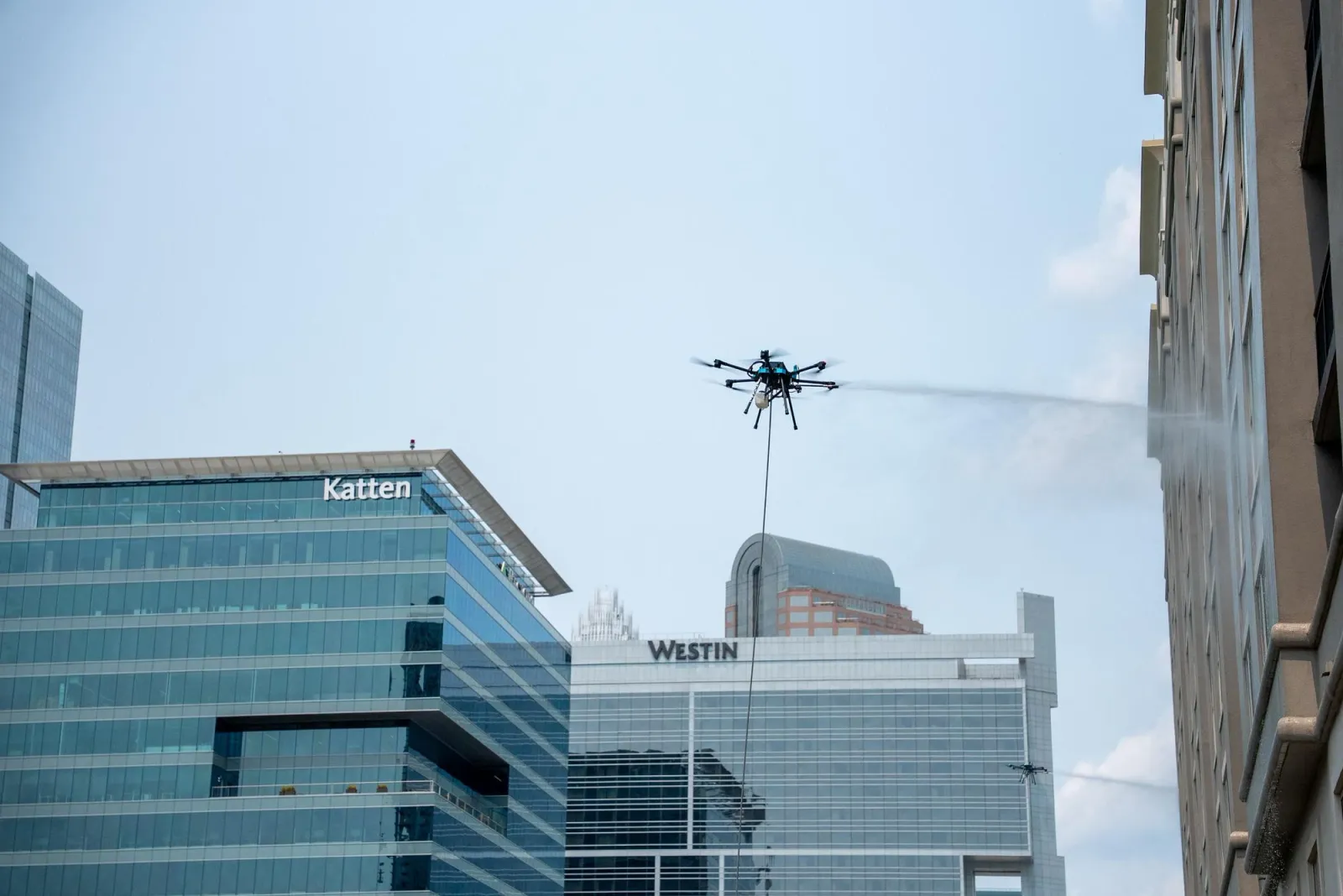 Lucid Bots Sherpa hexacopter drone cleaning a glass building facade at height